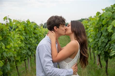 Casal apaixonado se beija enquanto estão no meio dos campos de uva