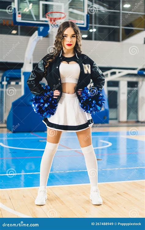 Full Vertical Shot Of Brunette Cheerleader In Black And White Uniform With A Jacket Posing With