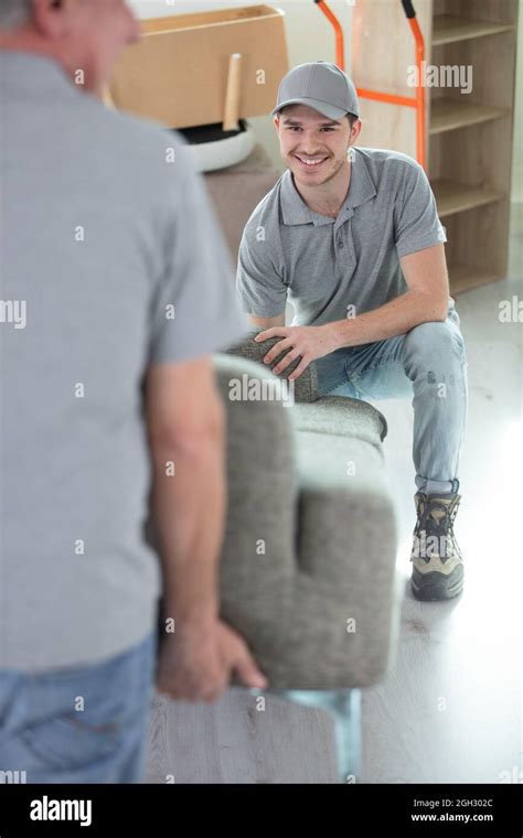 Two Happy Male Workers Carrying Sofa At Home Stock Photo Alamy