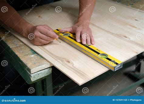 Carpenter Marking Straight Line On Plywood Sheet Using Spirit Level In