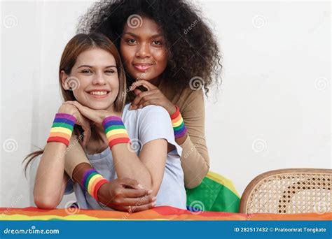 Happy Smiling Homosexual Lesbian Couple With Rainbow Flag Wristband Hugging Each Other