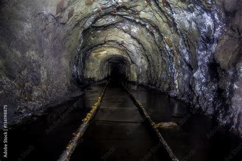 Flooded Tunnel Of An Old Abandoned Coal Mine With Rusty Remnants Of