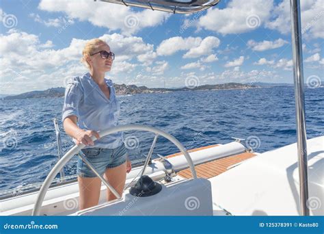 Attractive Blond Female Skipper Navigating The Fancy Catamaran Sailboat