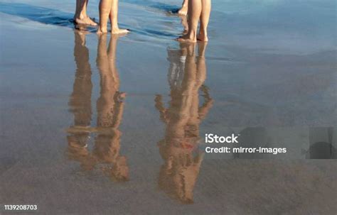 Young Bathers In Bathing Suits Reflection On Freshly Wet Sand Stock