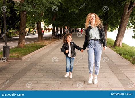 The Mom And Little Girl Walk Together Along The Waterfront Stock Photo