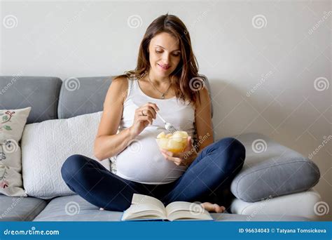 Schwangere Frau Der Junge Zu Hause Sitzend Auf Der Couch Und Essen Melone Stockbild Bild Von