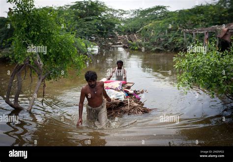 Pakistani Flood Survivors Carry Their Belongings Retrieved From Their