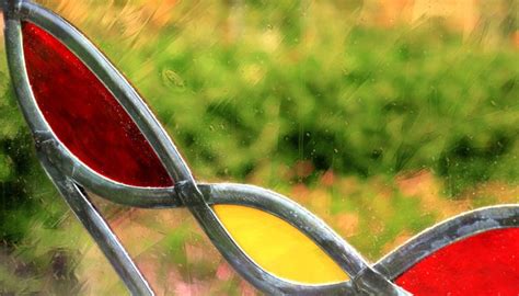 A Close Up View Of A Stained Glass Window With Green Grass In The Back