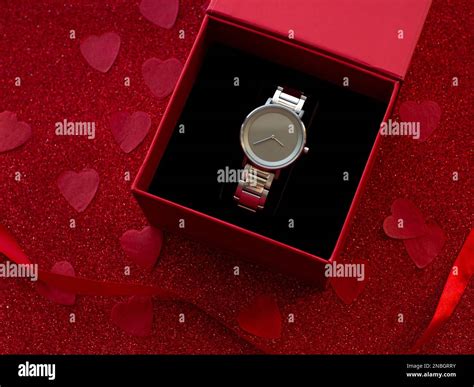 T Box With Silver Watch Is On Red Heart Paper Background Top View