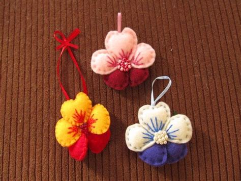 Three Small Felt Flower Ornaments On A Brown Surface