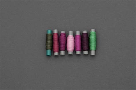 Premium Photo A Row Of Spools Of Thread With Different Colors