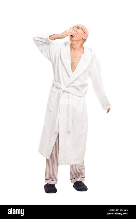 Full Length Portrait Of A Sleepy Senior Man In A White Bathrobe Yawning