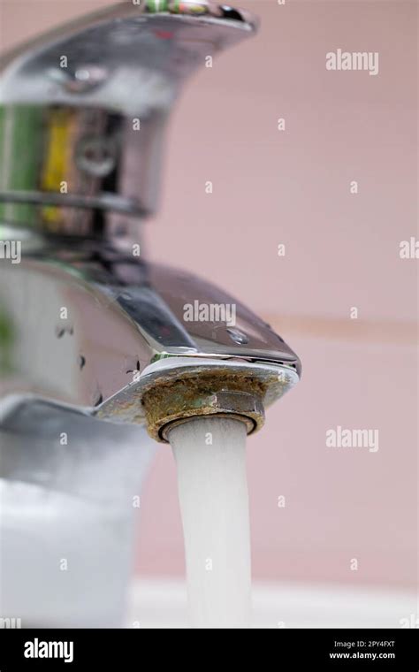 Vertical Close Up Flowing Tap Water On Pink Tiled Background Faucet