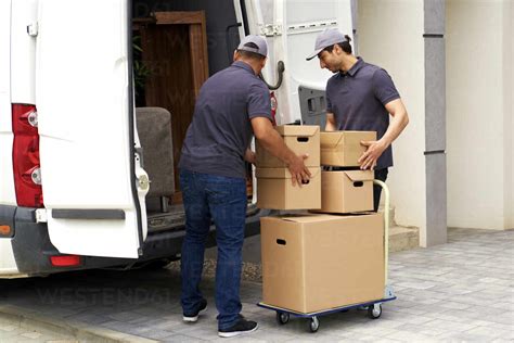 Male Delivery Persons Loading Boxes In Moving Van Stock Photo