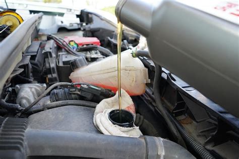 Premium Photo Pouring Oil To The Car Car Mechanic Holding A Bottle Of