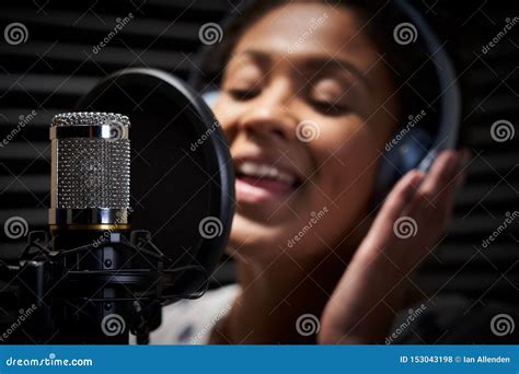 Female Vocalist Wearing Headphones Singing Into Microphone In Recording