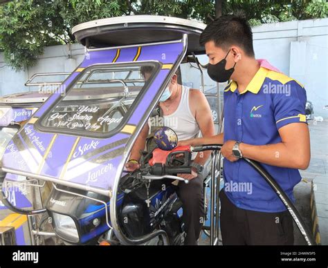 Un triciclo está siendo repostado por un asistente de gasolina