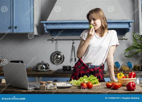 Young Girl Prepares A Vegetarian Salad In The Kitchen She Looks Into A