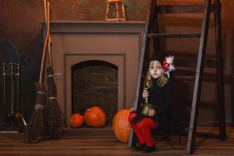 Premium Photo A Girl In A Witch Costume Sits Near The Fireplace