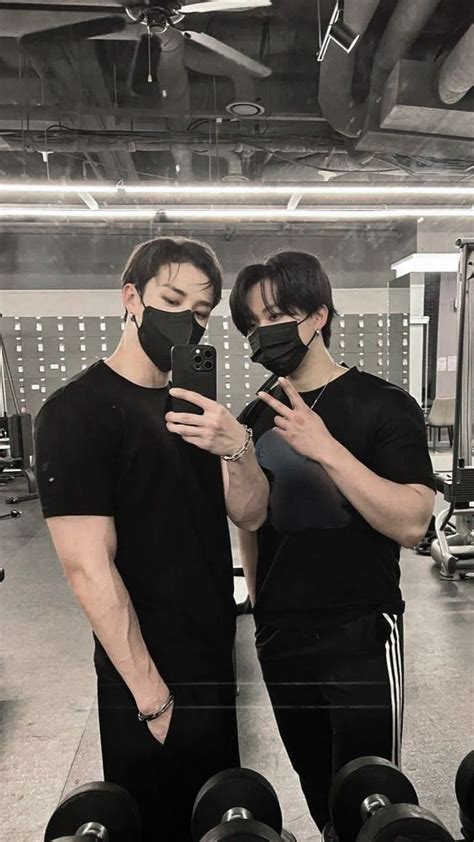 Two Men In Black T Shirts And Face Masks Are Looking At Their Cell Phones