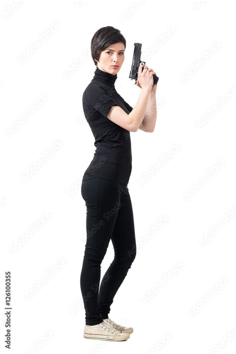 Side View Of Armed Tough Woman Holding Gun Looking At Camera Full Body