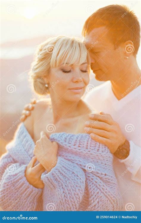 Man Hugs Woman From Behind By The Shoulders Touching Her Temple With