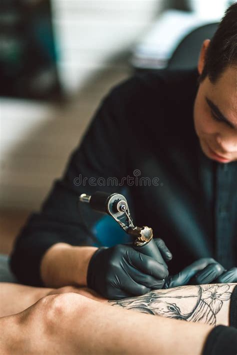 L Artiste Masculin De Tatouage Fait Un Tatouage Sur Une Jambe Femelle