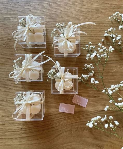 Four Small Clear Boxes With Flowers And Soaps In Them On Top Of A