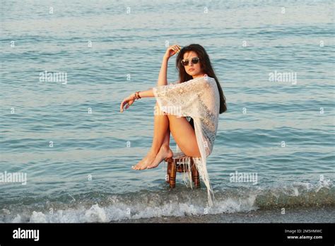 Une jeune belle femme pose sur la plage de l océan Jolie brunette en tunique blanche de plage
