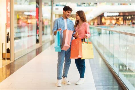 Pareja Alegre Con Bolsas De Compras Comprando Ropa De Pie En Un Centro