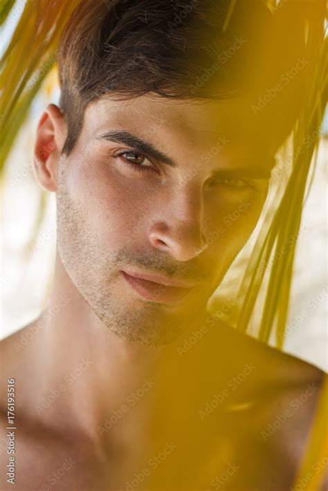 Handsome Mature Male Model Standing Topless Under Palms On The Beach