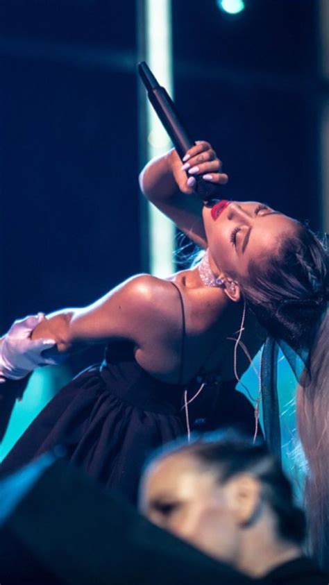 A Woman In A Black Dress Holding A Cell Phone Up To Her Ear While