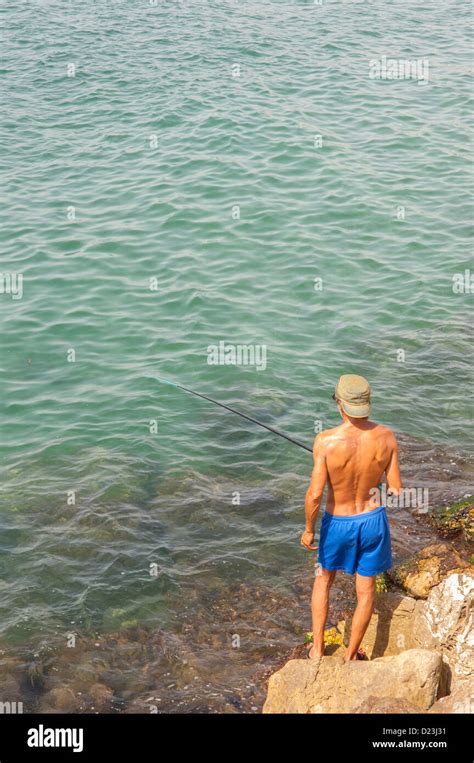 A man fishing with a rod at the fishing port of Cambrils , Costa Dorada , Spain Stock Photo - Alamy