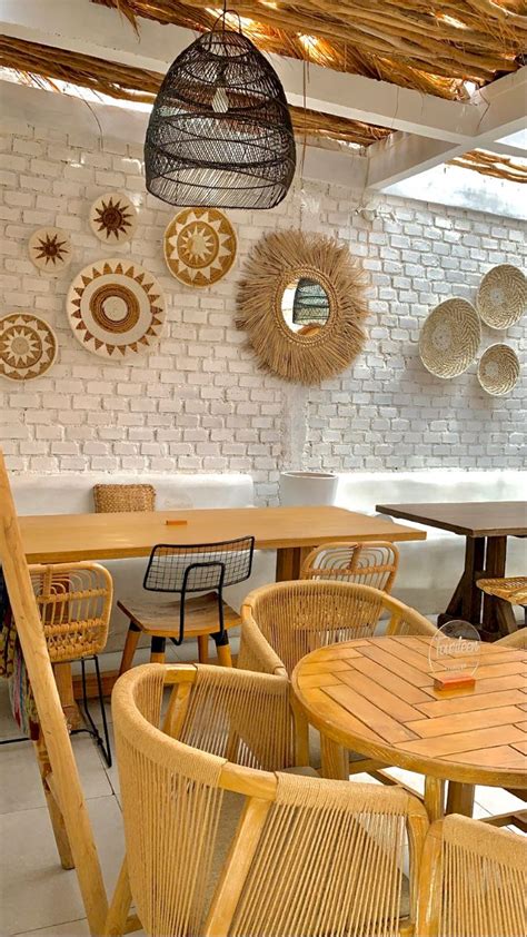 An Outdoor Dining Area With Wicker Chairs And Round Wooden Tables In