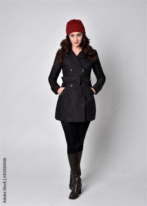 Full Length Portrait Of A Pretty Brunette Girl Wearing A Black Coat