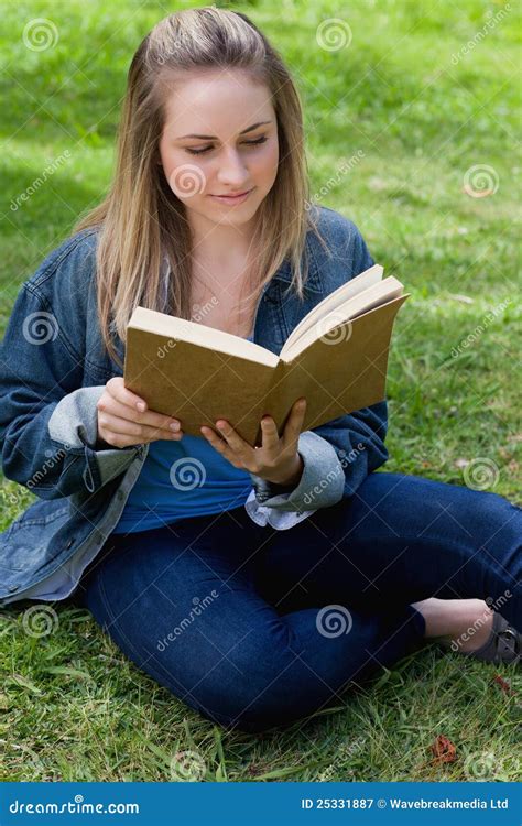 Young Relaxed Girl Reading A Book While Sitting On The Grass Royalty