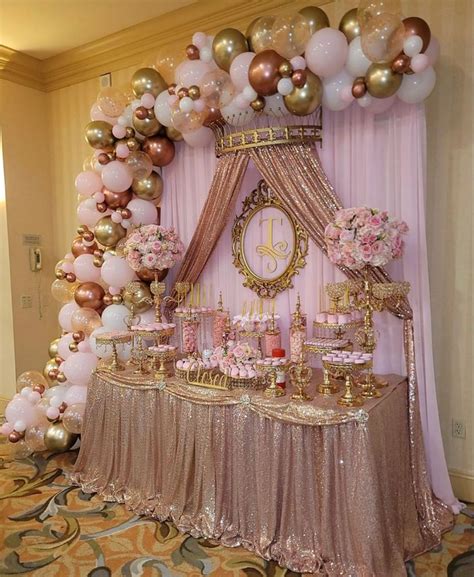 A Table Topped With Lots Of Pink And Gold Balloons Next To A Clock On A