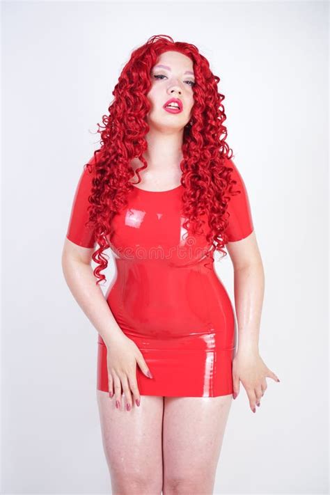 Hot Sexual Redheaded Girl With Plus Size Body Wears Fashion Latex Rubber Red Dress And Posing On