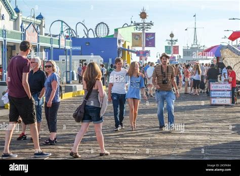 People Enjoy A Sunny Day At Iconic Santa Monica Pier On The Pacific Coast Beach In Santa Monica