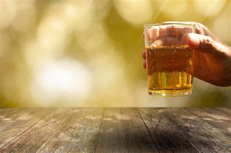 Premium Photo Hand Holding Glass Of Beer On Table