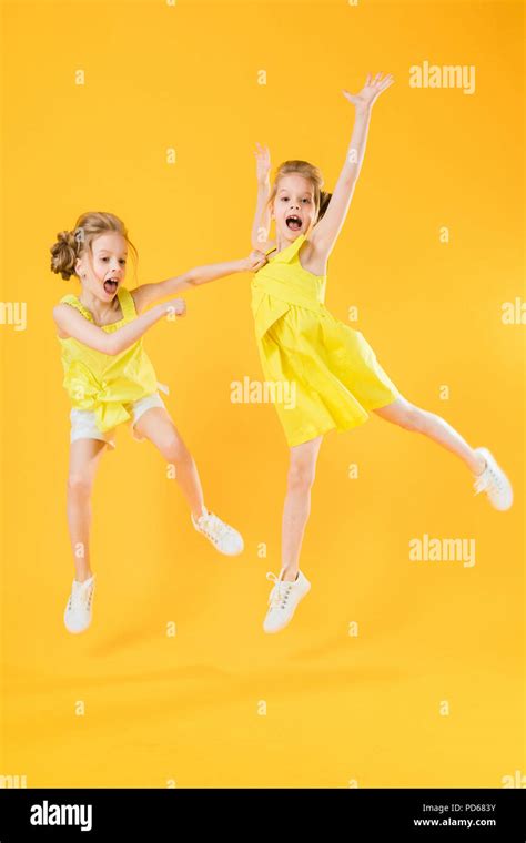 The girls of the twins are dancing together on a yellow background ...