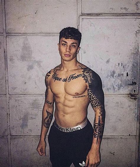 A Man With Tattoos Standing In Front Of A Door