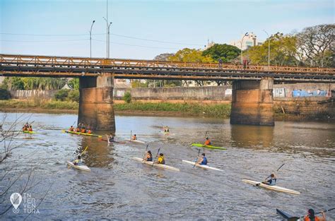 A Group Of People In Kayaks Paddling On The Water Under A Bridge Overpass