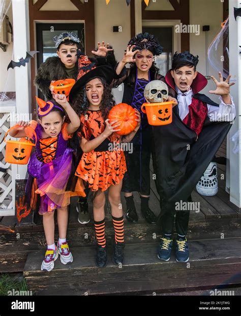 Multiethnic children in halloween costumes holding buckets and ...