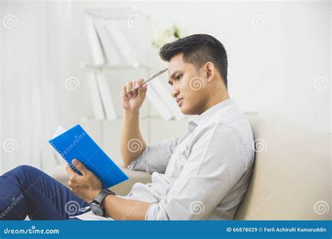 Young Man Thinking While Writing On A Book Stock Image Image Of