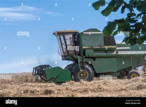 John Deere Combine Harvester Cutting Wheat Crop In Summer Sun Front