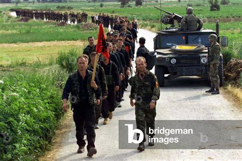 Image of A column of Kosovo Liberation Army fighters march with their