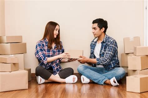 Premium Photo Couple Holding Cardboard Boxes While Sitting On Floor