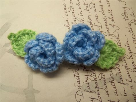 Two Crocheted Flowers Sitting On Top Of An Open Book With Writing In