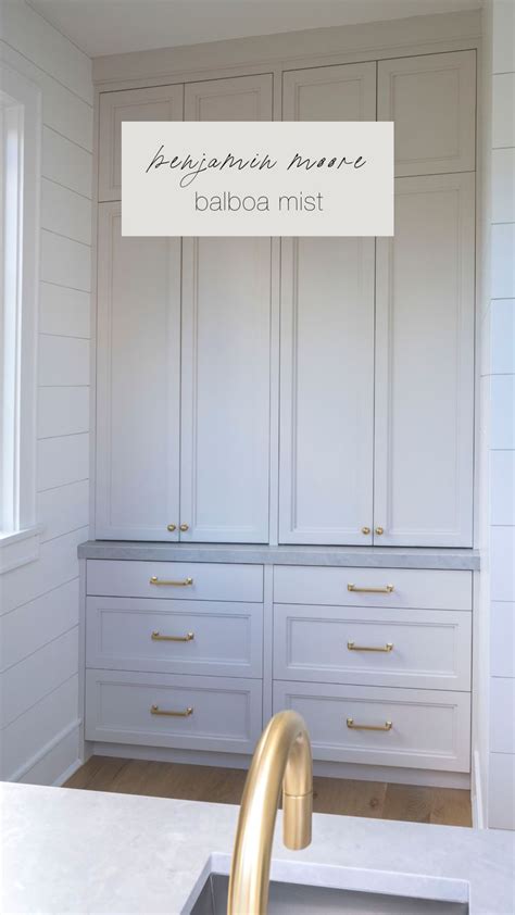 A Kitchen With White Cabinets And Gold Faucet